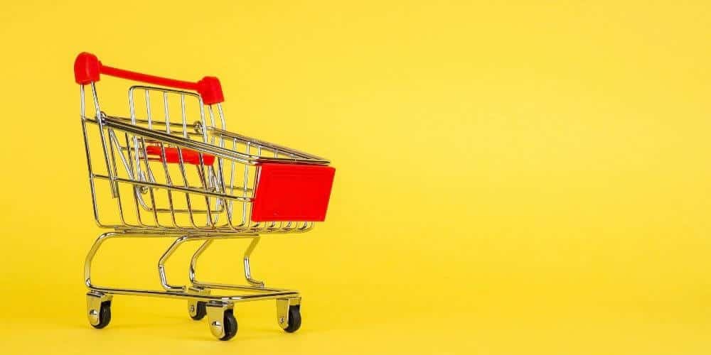 save money on groceries-toy shopping cart on yellow background