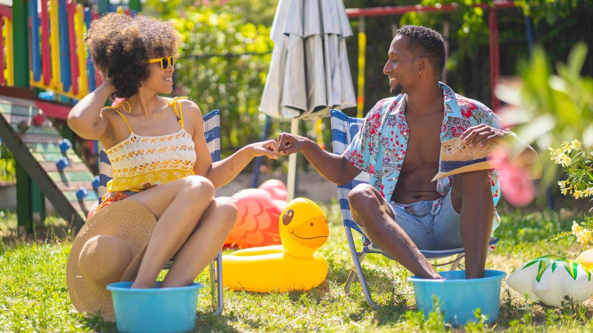 graphic of young black couple sitting in lawn chairs in backyard soaking feet in buckets staycation ideas to save money